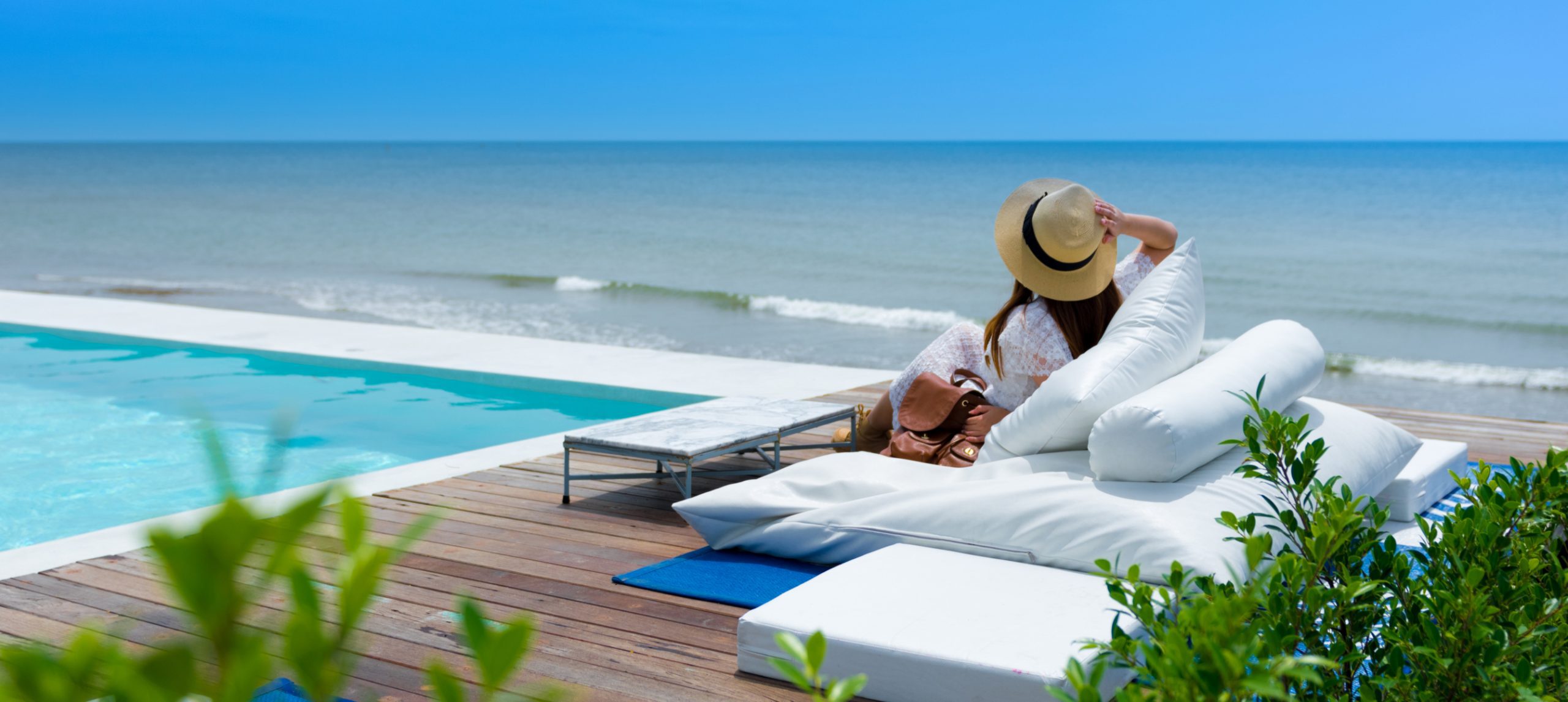 A young woman relaxing at an oceanfront pool deck.