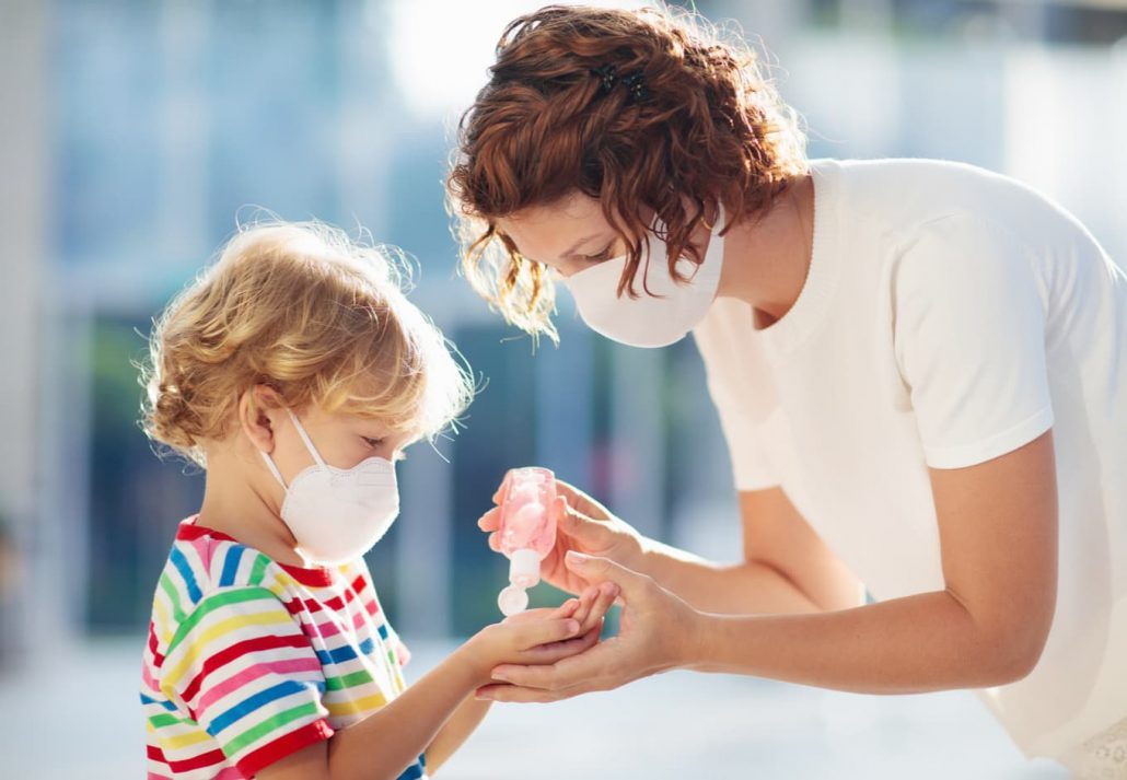 A mom aplying giving her child hand sanitizer