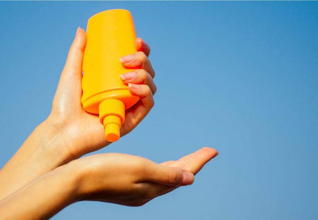 Woman applying sunscree on her hand on a sunny summer day.
