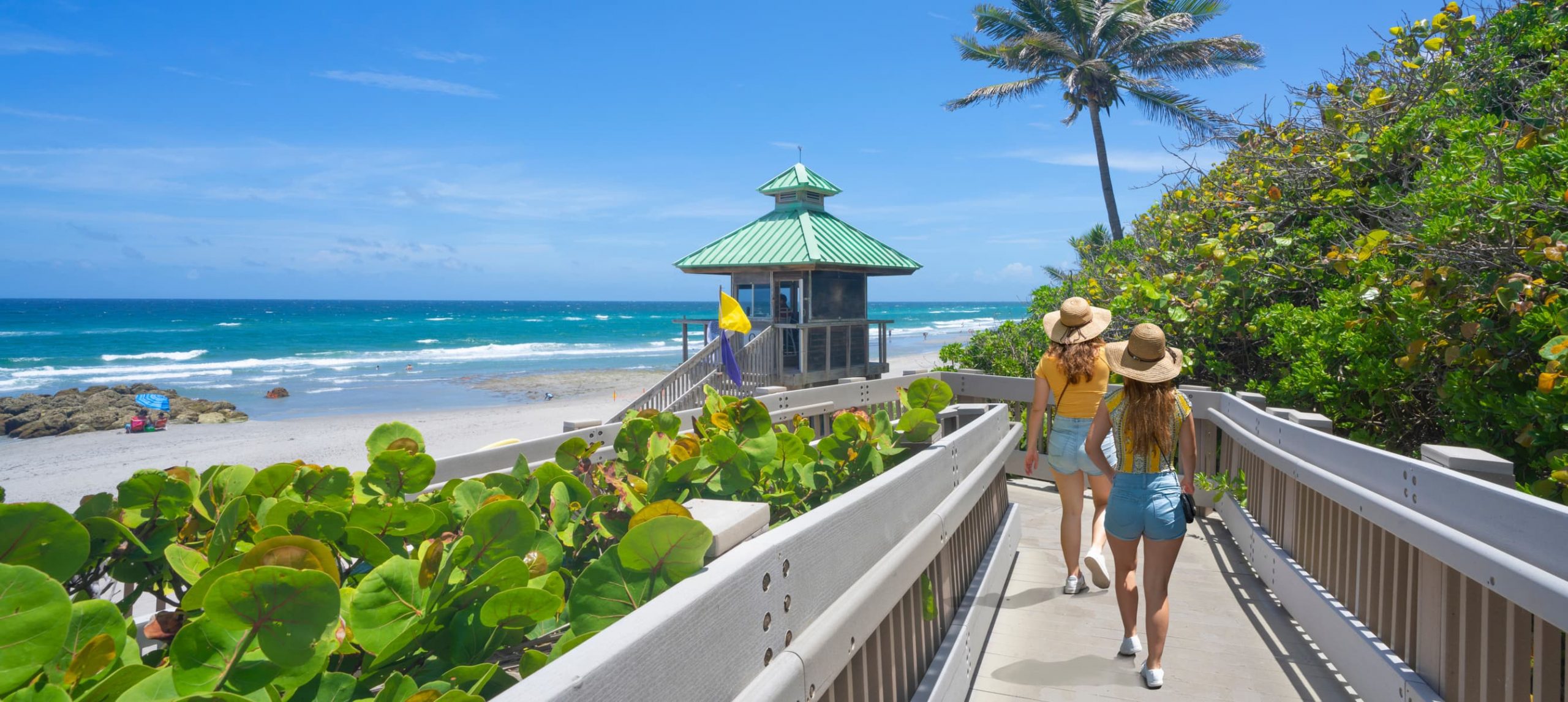 Women walking on boardwalk to beautiful Florida beach.