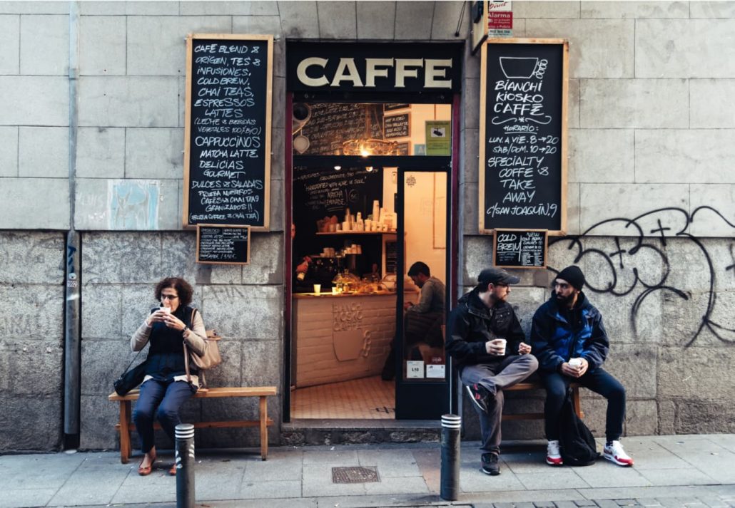 People drinking coffee outside hipster cafe in Malasaña district in Madrid, Spain.