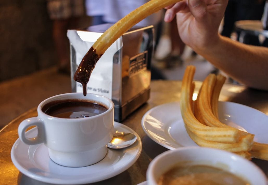 Person eating Churros In Chocolatería San Ginés, Madrid, Spain.