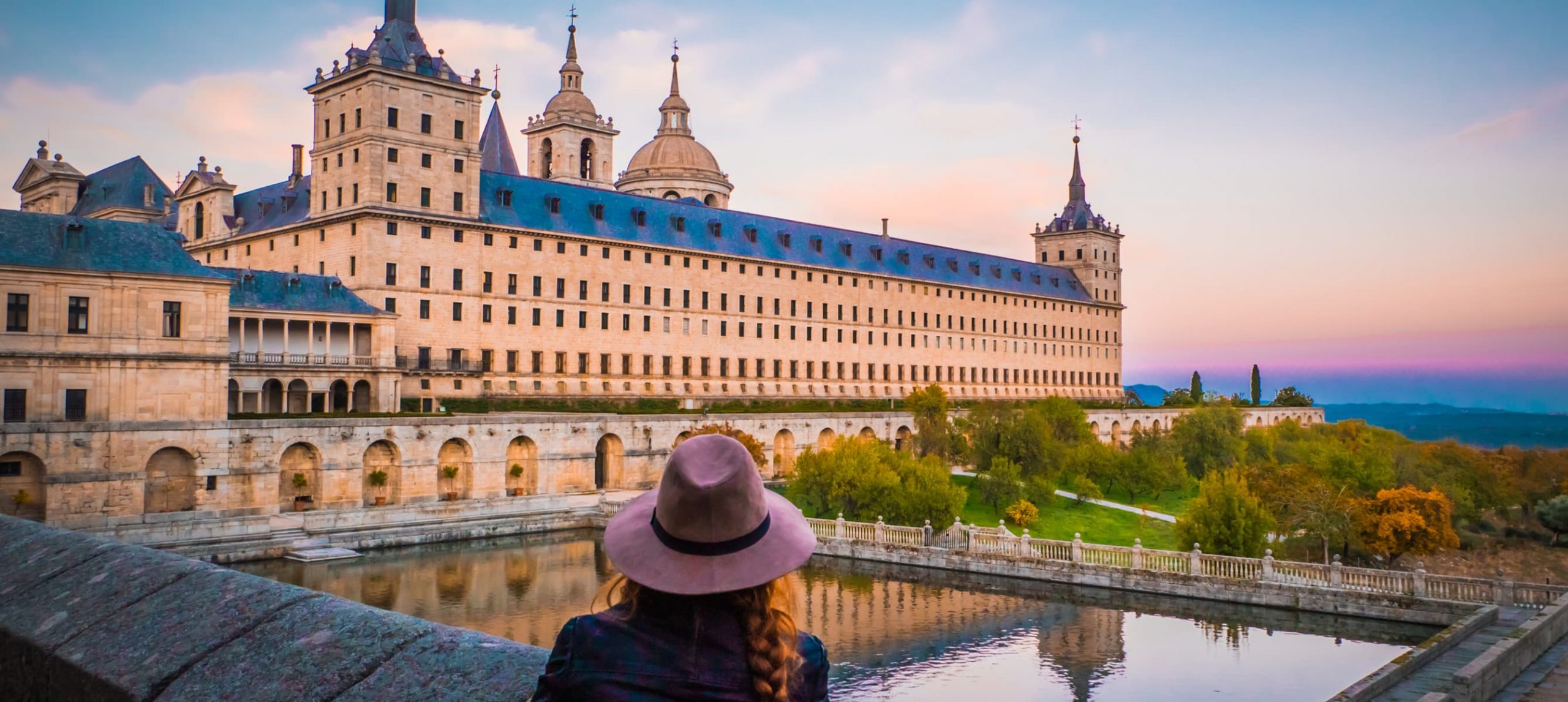 Young woman marveling at the Monastery of San Lorenzo de El Escorial, Spain.