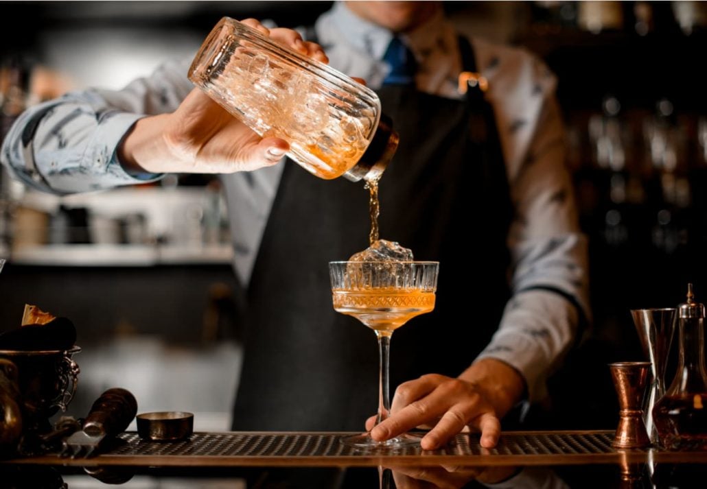 Barman with tattoo making a fresh and sweet summer cocktail