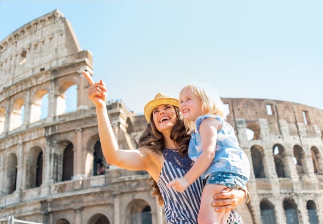 A woman carrying her daughter while visiting the Colosseum, in Rome