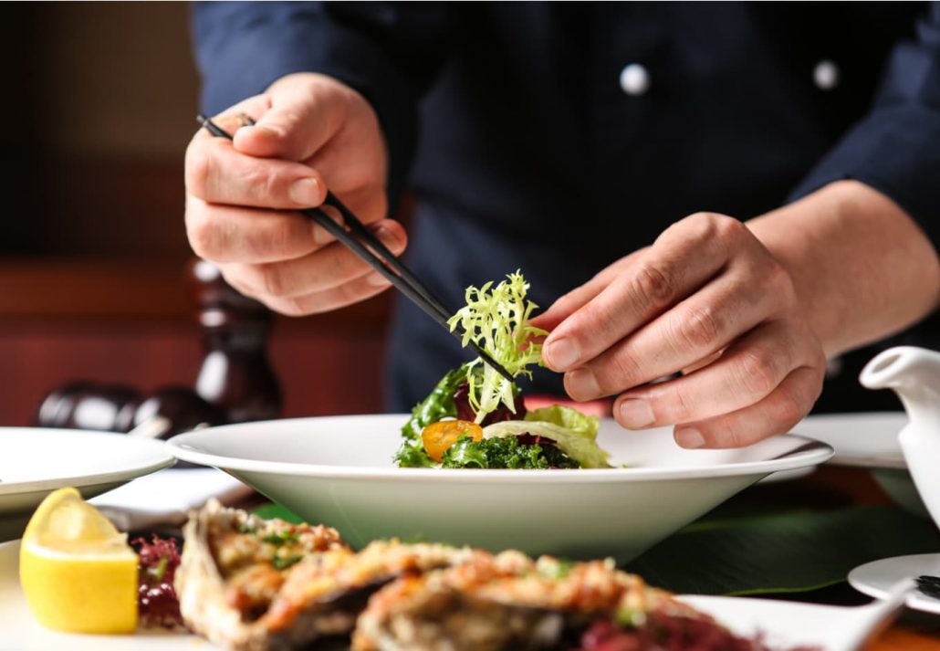 Chef using chopsticks to carefully prepare a gourmet dish 