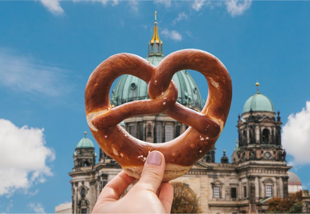 Young woman holding a pretzel in front of the Berlin Cathedral, in Germany.
