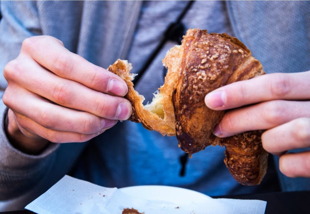 Male hands holding a cornetto, an Italian-style brioche.