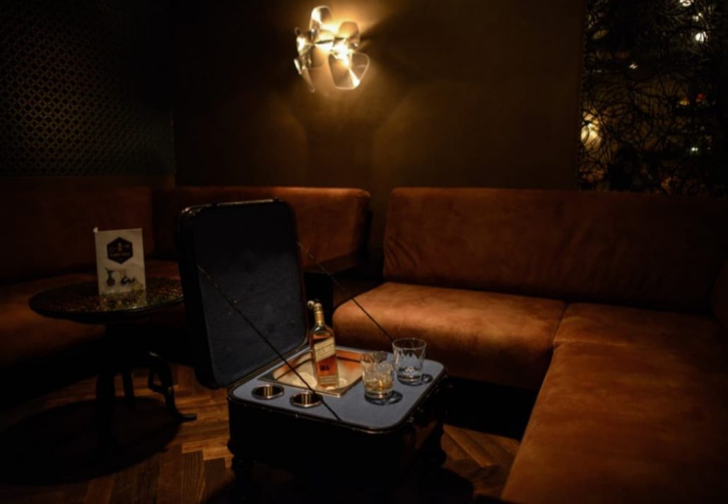 A lounge area in Fairytale Bar, Berlin with a trunk as a table and a whiskey bottle on it