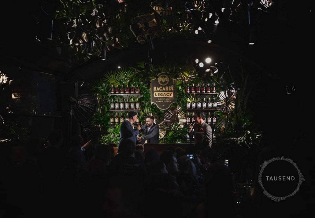 Two male singers performing in front of the crowd with a mixologist in the background in Tausend Bar, Berlin