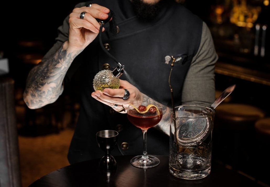 Tattoed bartender praparing a drink at a speakeasy