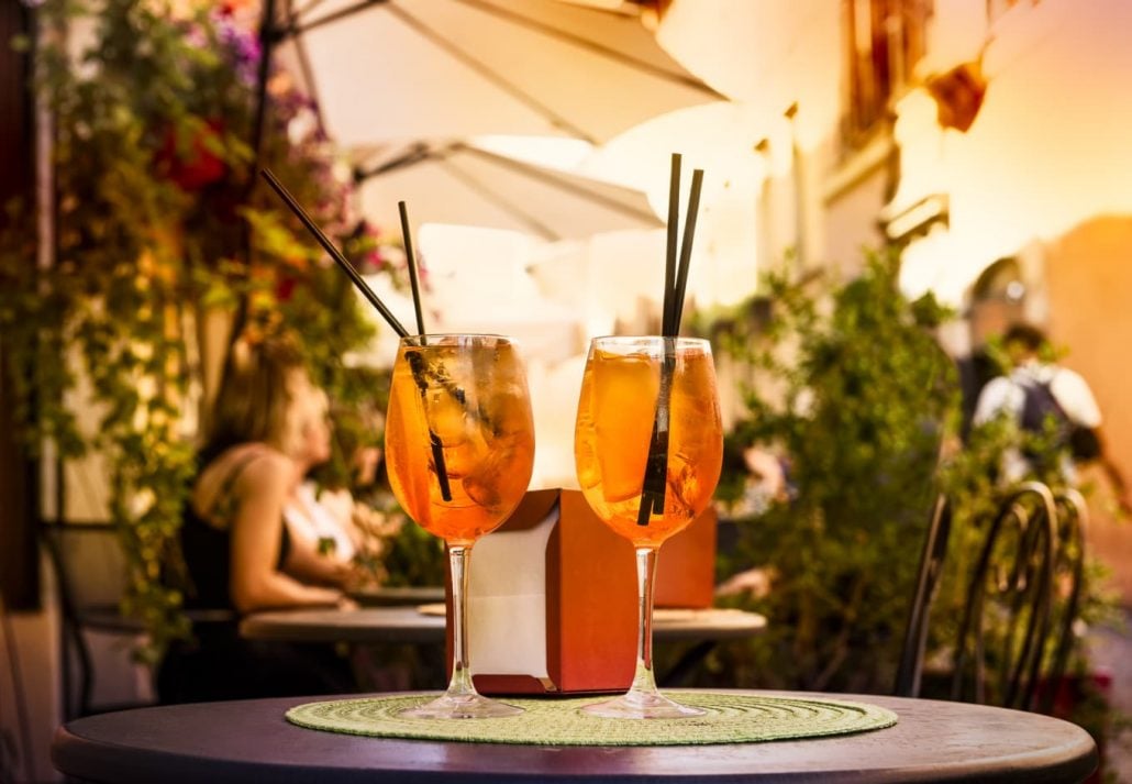 Two glasses of aperol spritz on a table top in a breezy bar