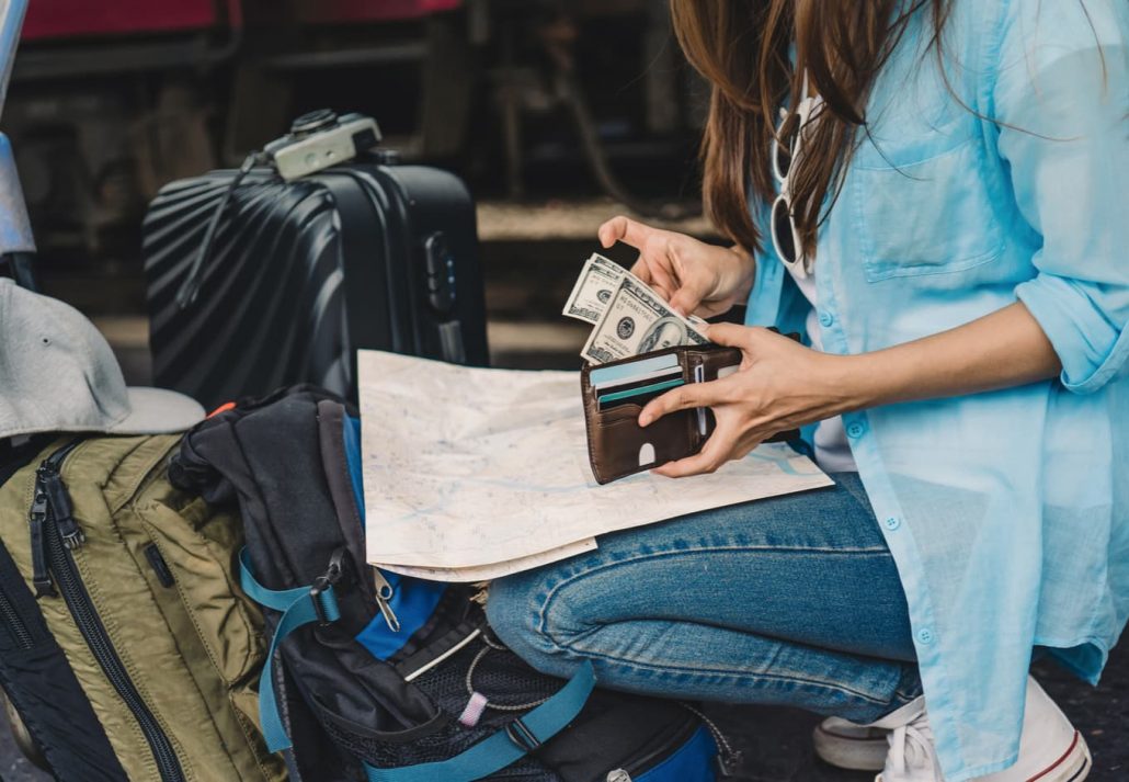 Young woman holding her wallet and counting dollar bills.