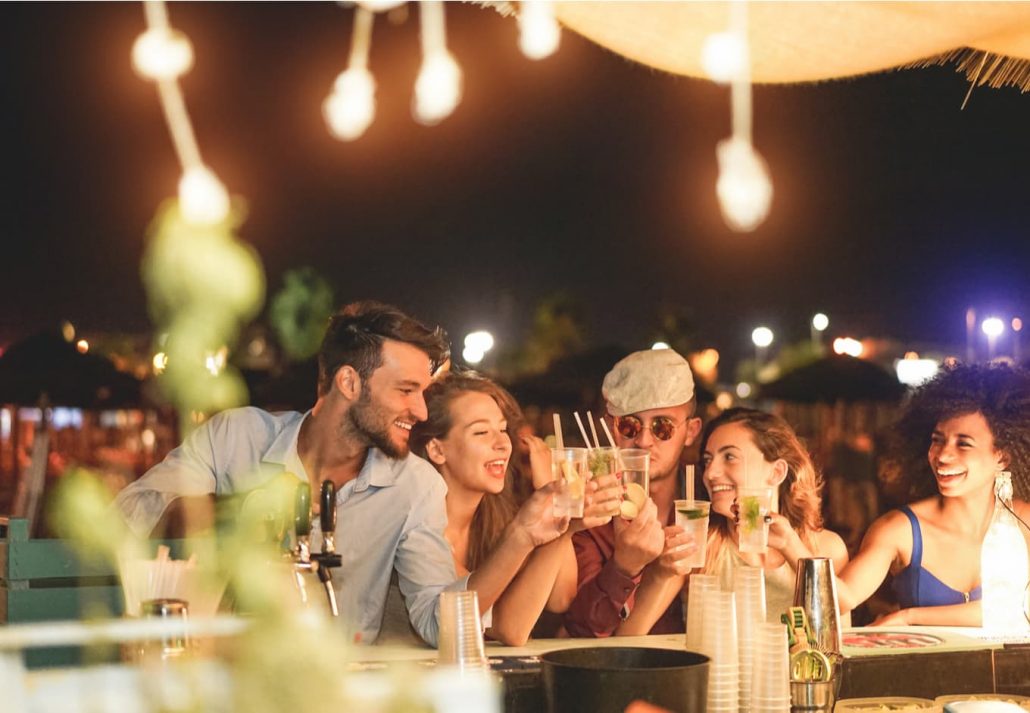 A group of 4 friends drinking and talking in a rooftop bar.