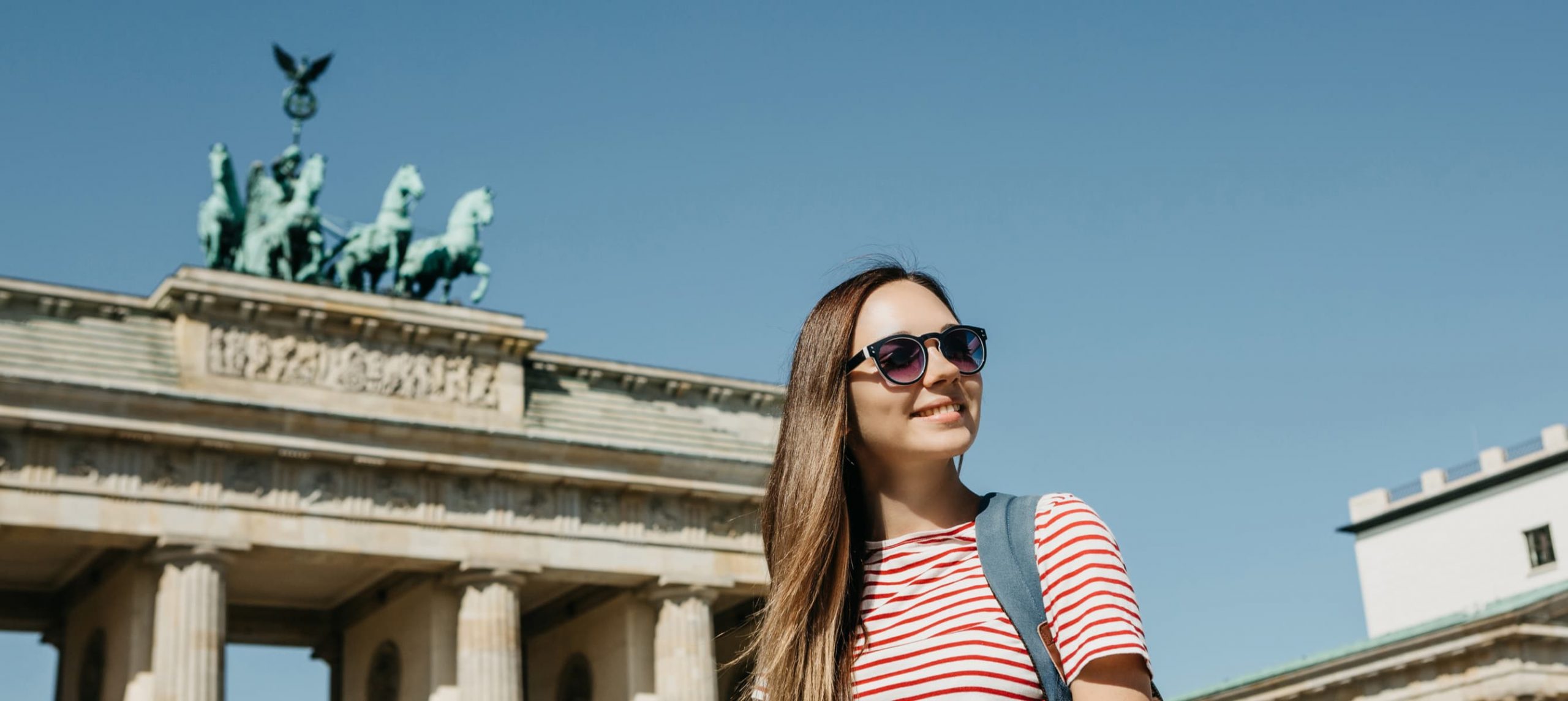 Berlin vs London: A female traveler in front of the Brandenburg Tor