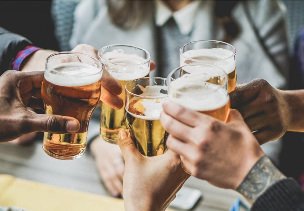 A group of people holding their full glasses of beer