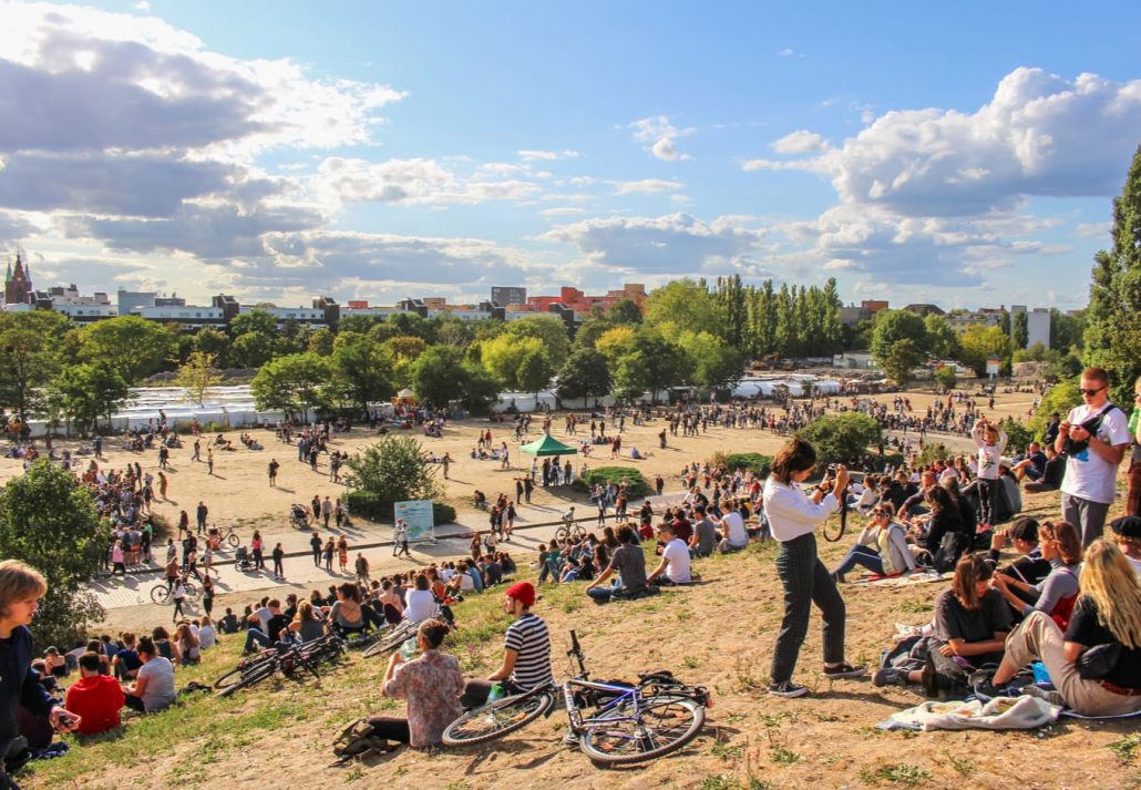 People sitting on the grass or walking around at daytime at Mauerpark