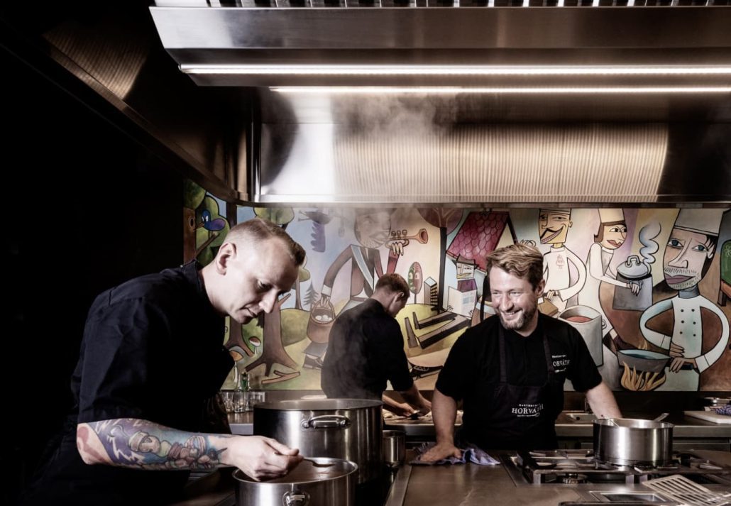 Three male chefs preparing food at Horvath's restaurant kitchen