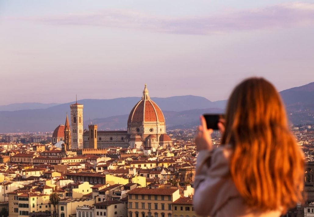 Young woman taking picture of the Cathedral of Santa Maria del Fiore, Florence, Italy.