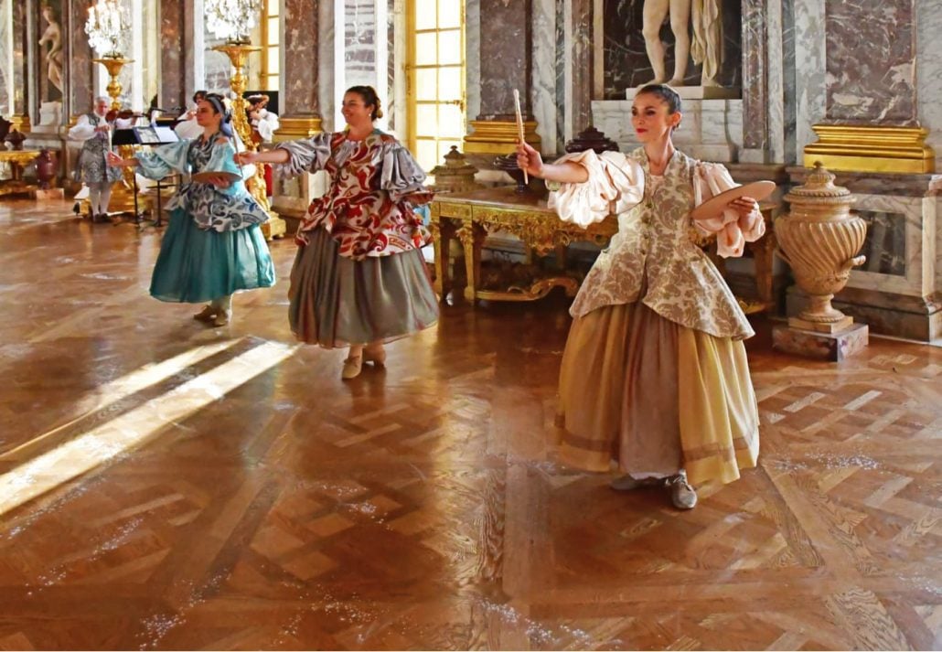 Women in ancient dresses posing for the public inside Versailles, France