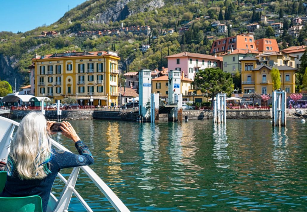 A female on a boat taking a photo of a small village in Lake Como