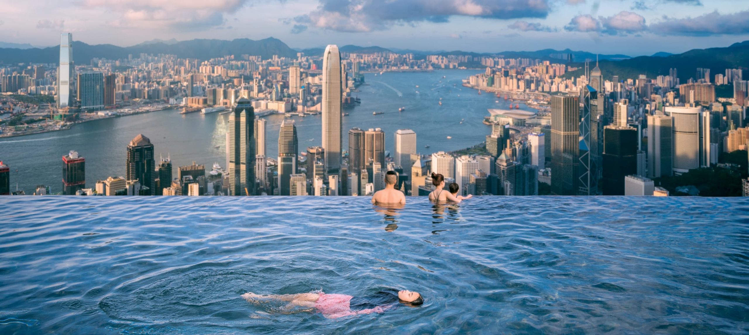 Three peope in an infinite swimming pool in Hong Hong.