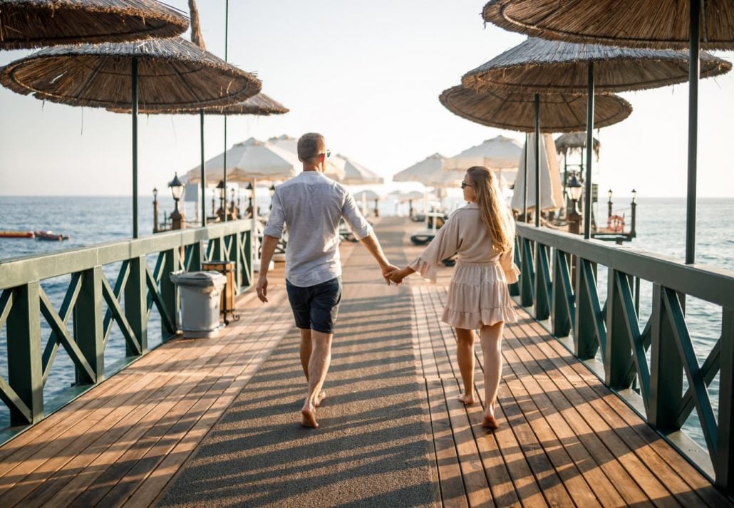 Young couple walking while holding hands in a beach resort, in Turkey.