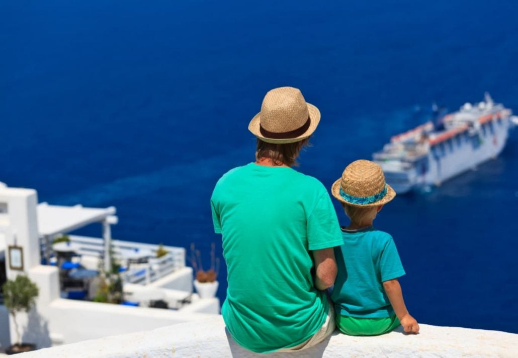 A child with a day sitting and looking at a ferry in the distance