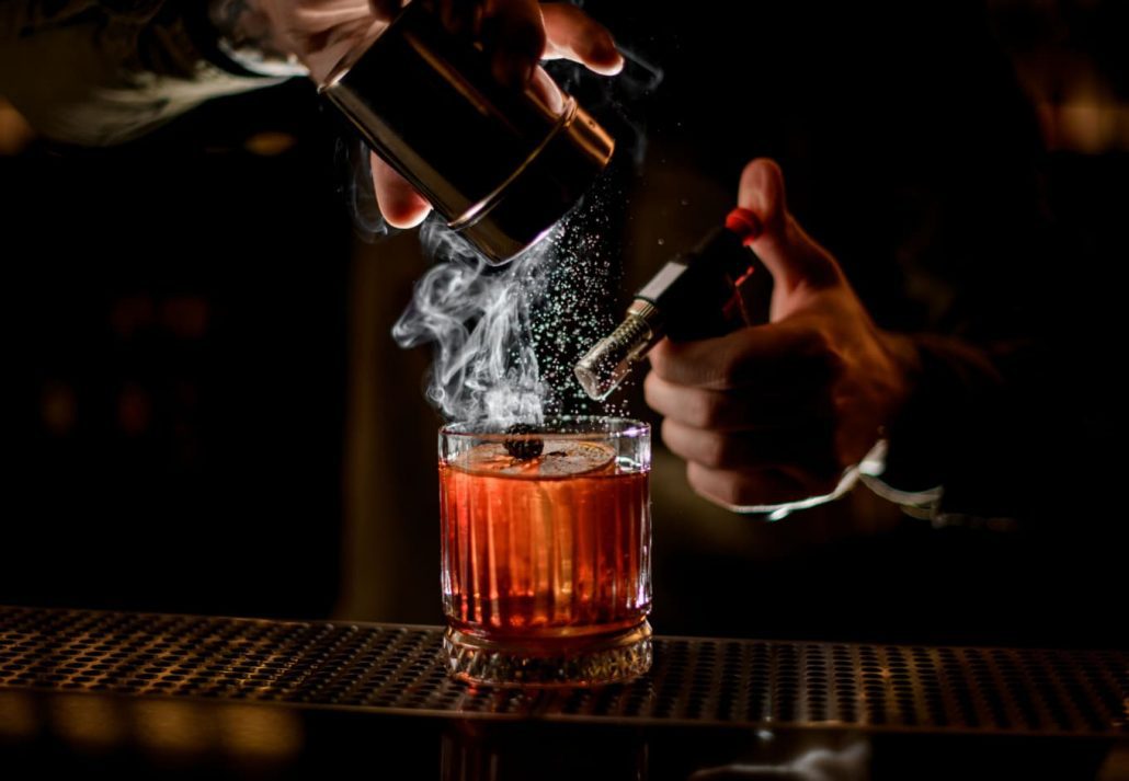 A mixologist smoking a cocktail glass