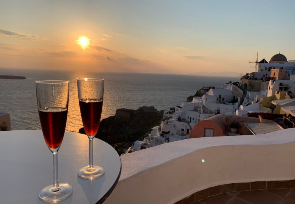 Two glasses of wine on a table with a view of Santorini
