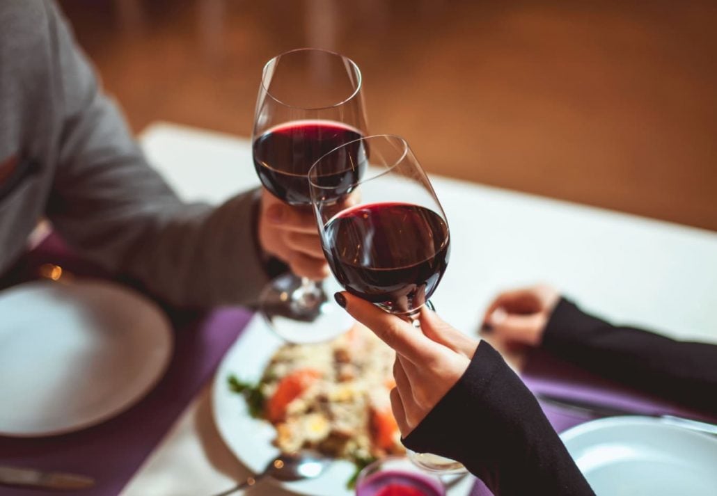 A man and a woman clincking with wine glasses