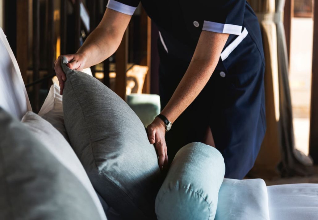 A housekeeper arranging pillows on the bed