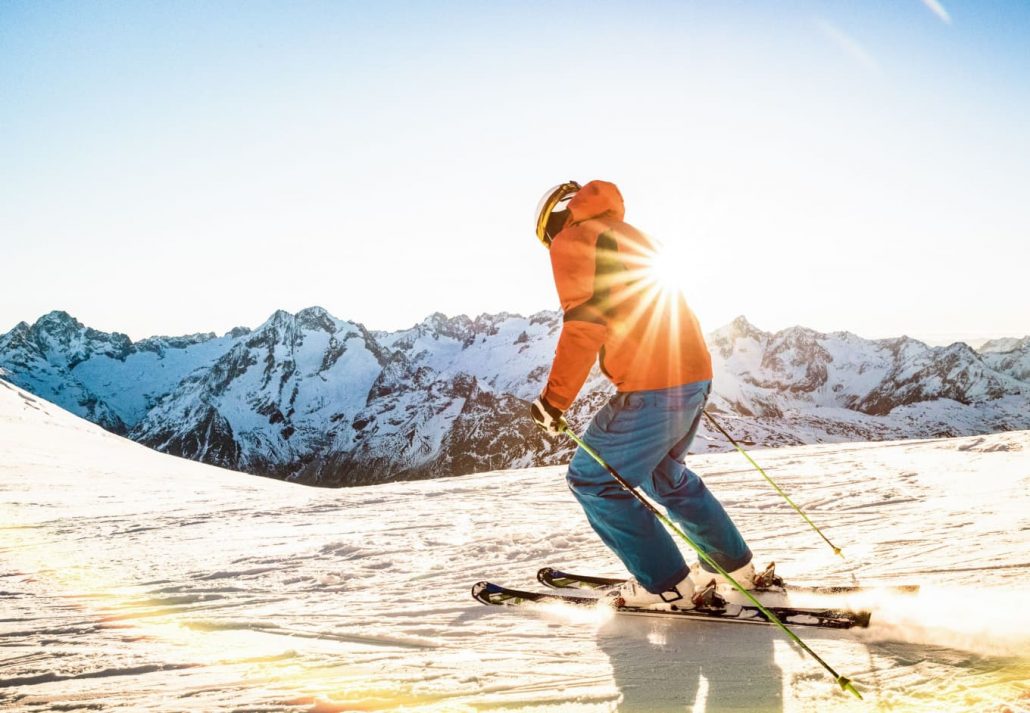 A man skiing down the mountain with sunrise in the background