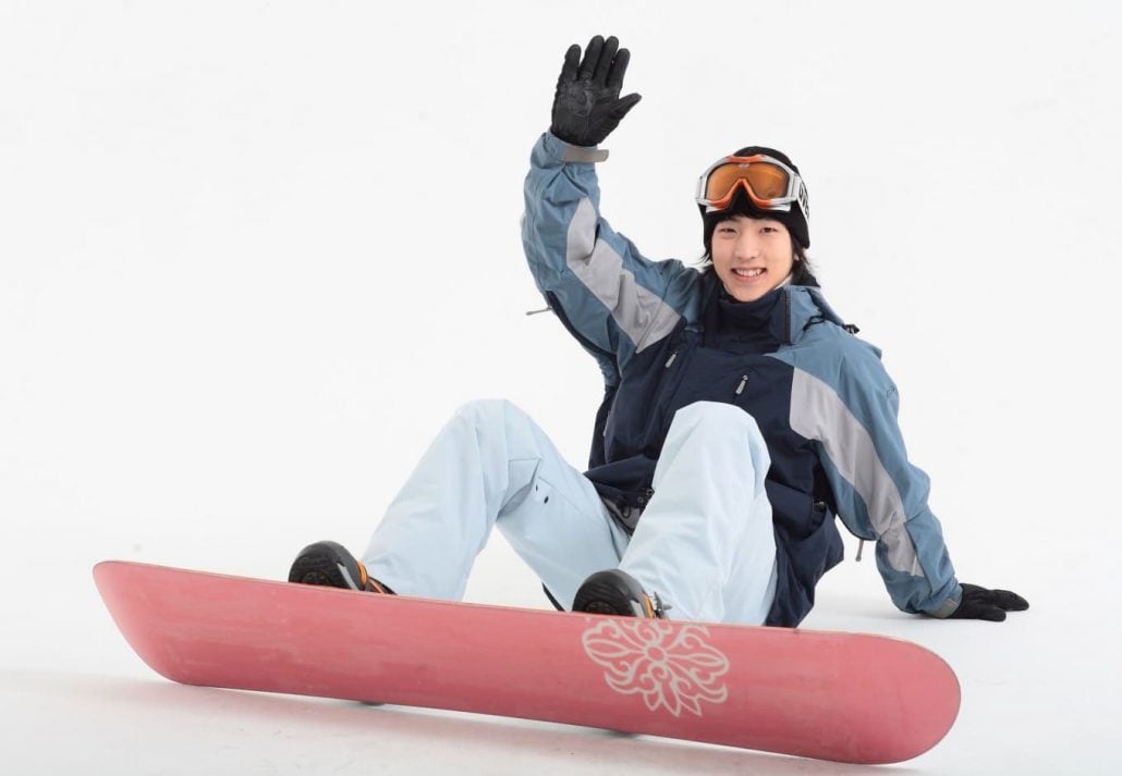 Young asian man snowboarding.
