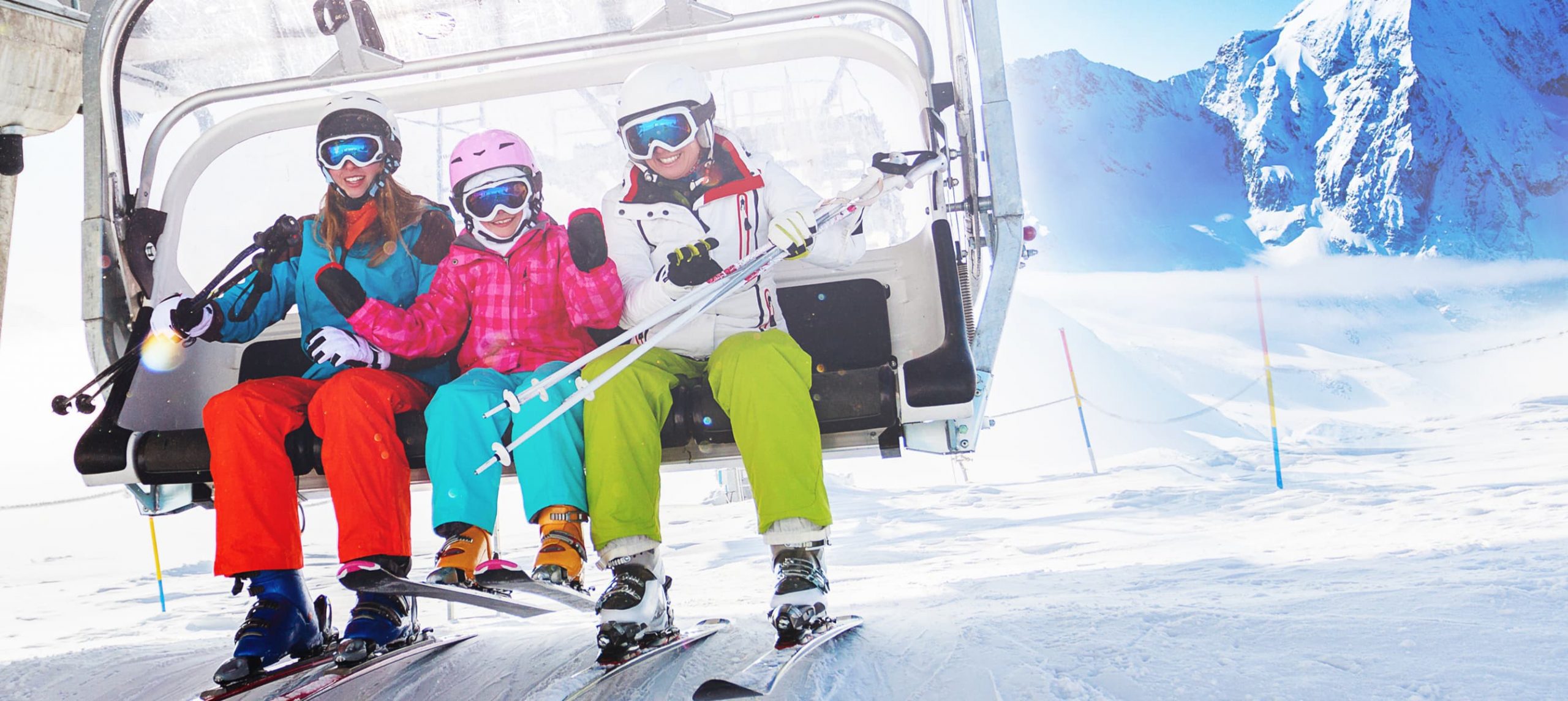 Three people on a ski lift in a snowy ski resort.