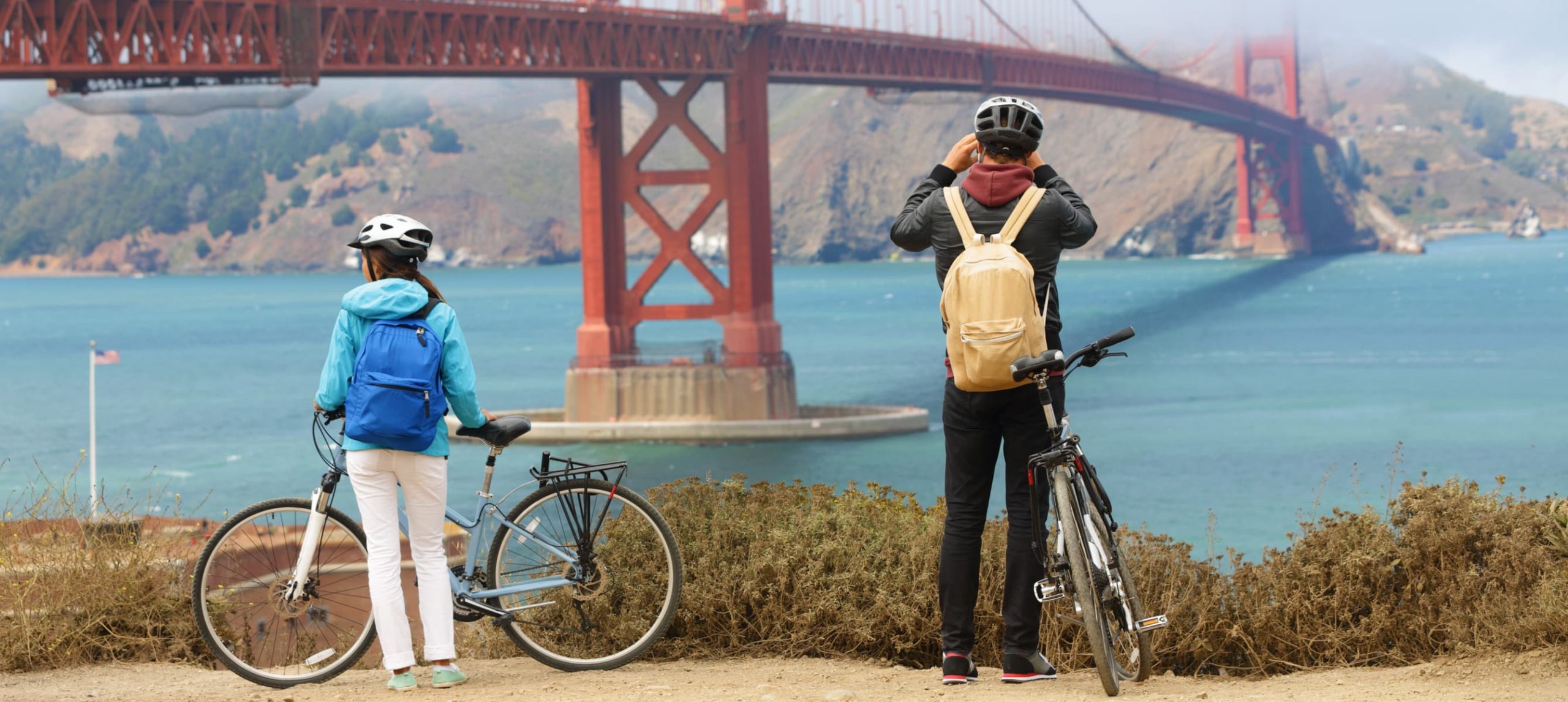 Young couple tourists on bike tour enjoying the view of the Golden Gate Bridge in California, USA.