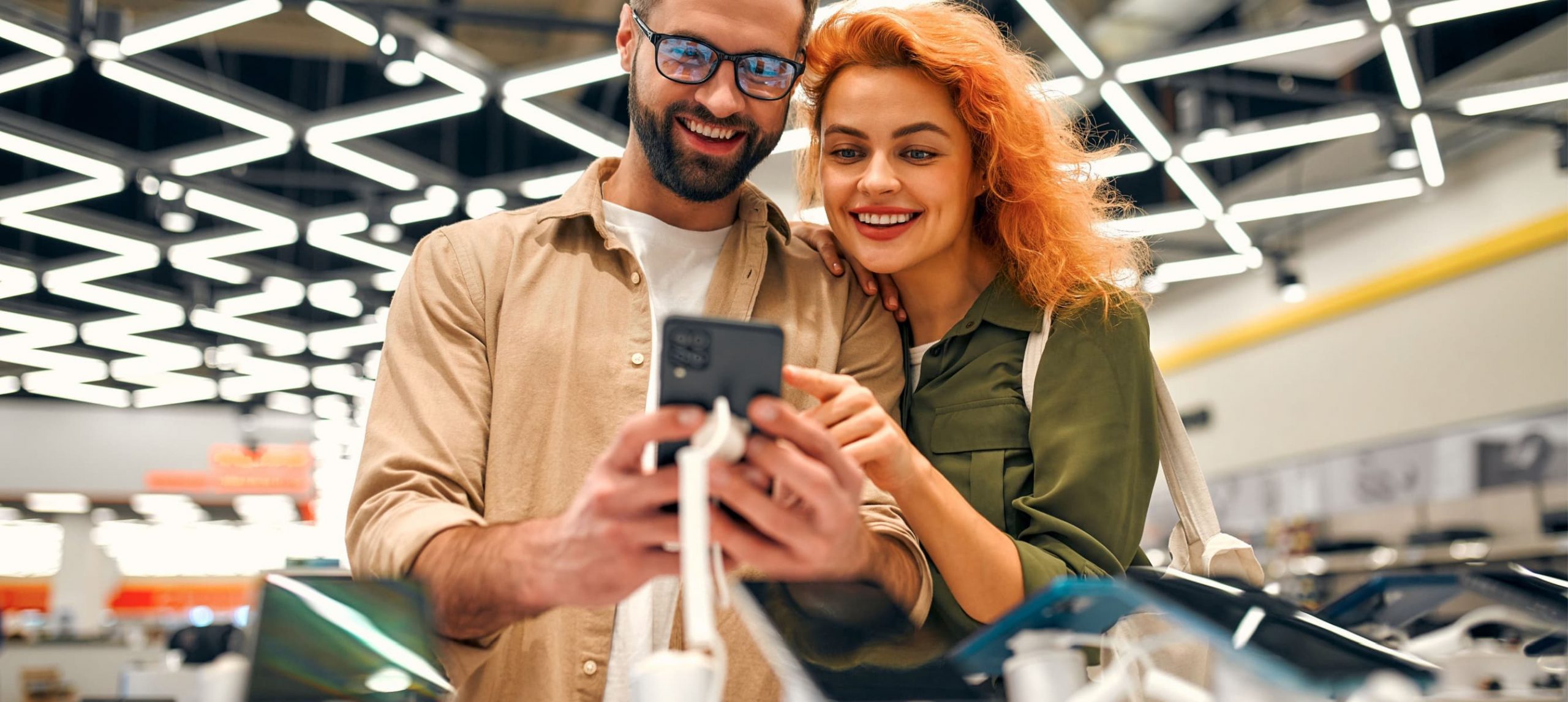 A couple happily buying electronic items together.