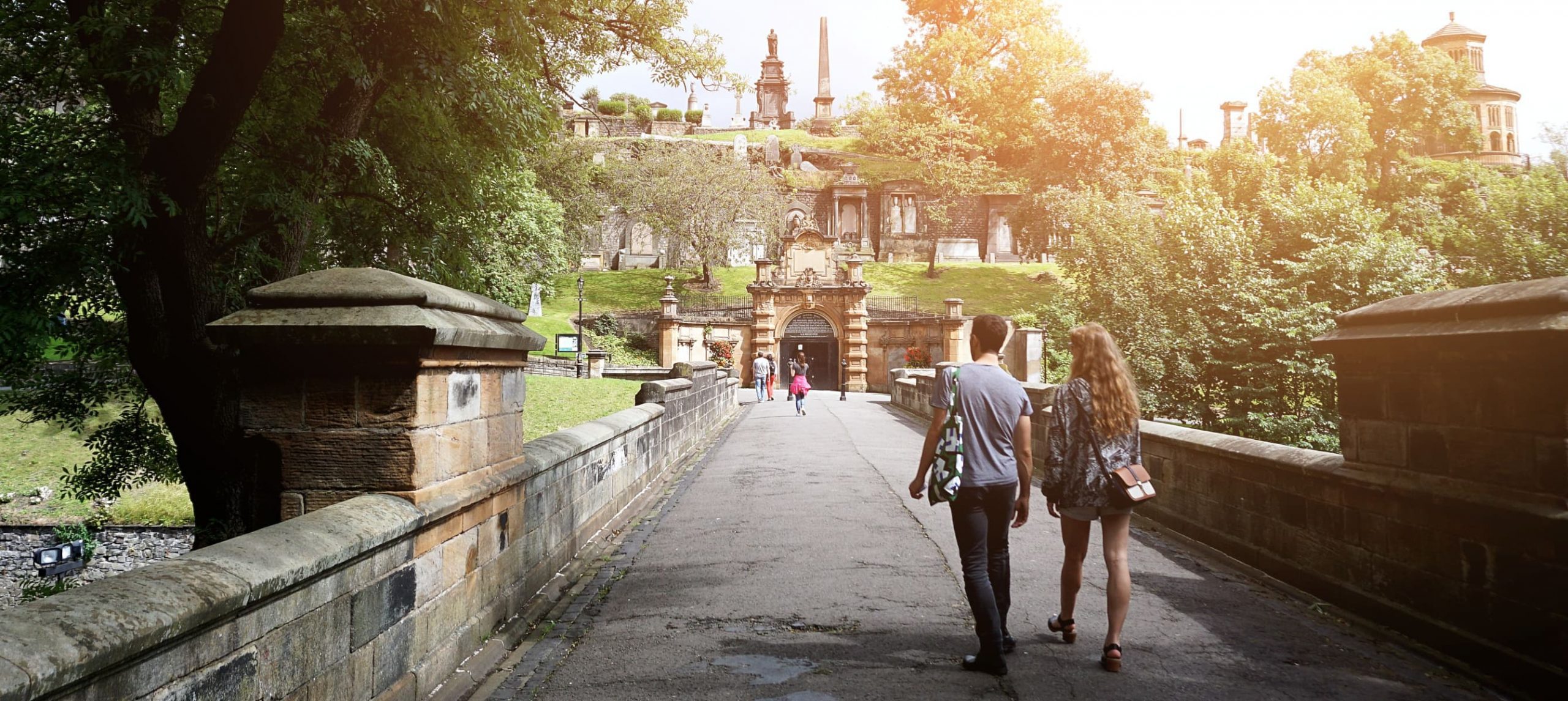 A couple walking towards the entrance to Glasgow Necropolis, Glasgow, Scotland, United Kingdom.