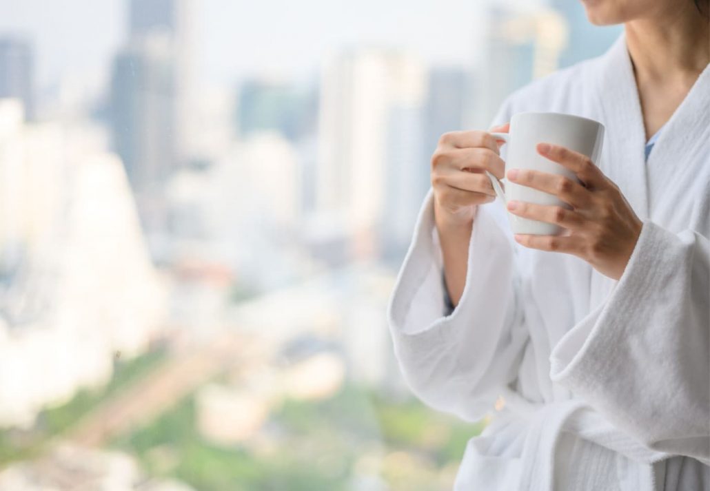 a woman in a hotel robe drinking coffee