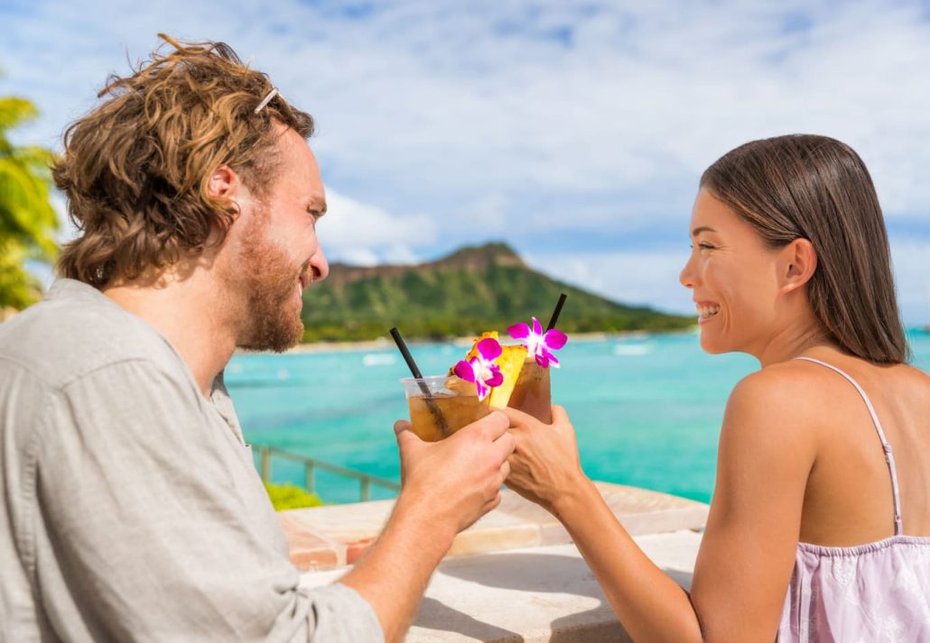 a couple drinking cocktails by the beach