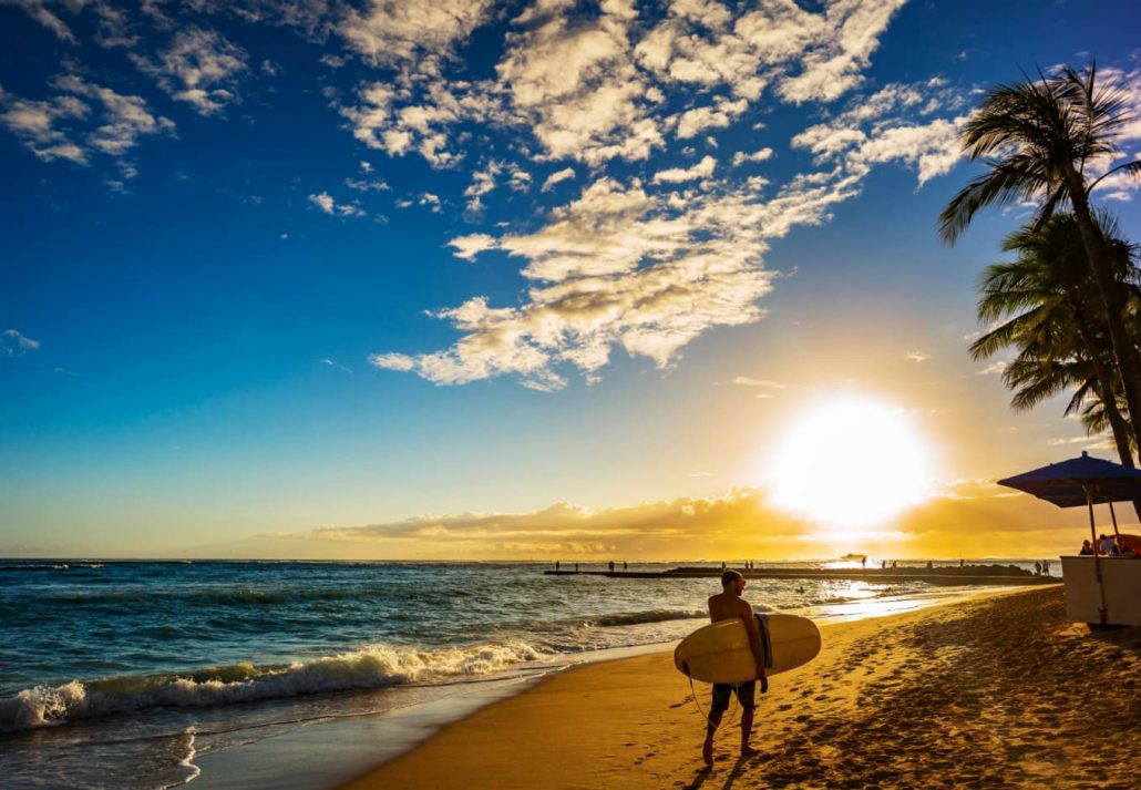 a man walking with a surfboard on the beach