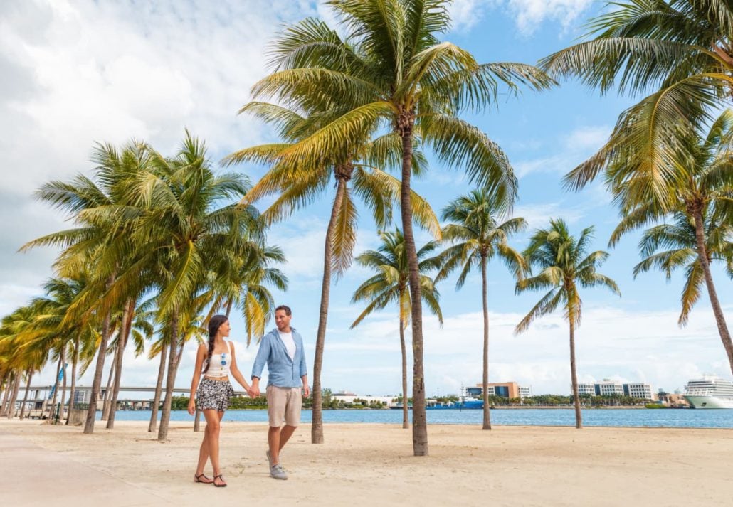 A couple happily walking in a palm-lined boulevard in Miami, Florida.