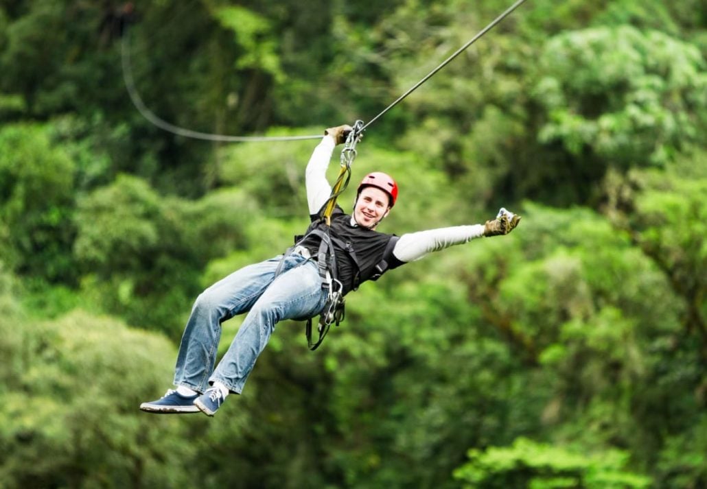 A man ziplining in a forest.