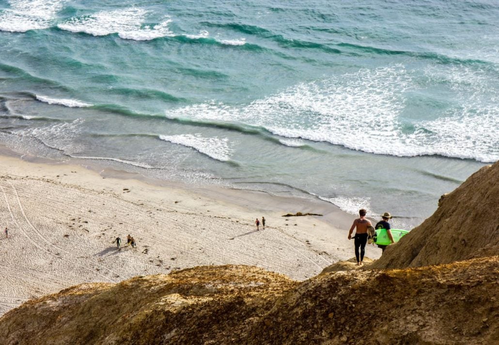 Surfers climb down the mountain to surf in the ocean near Torrey Pines in La Jolla, CA.