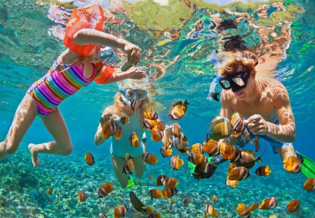 Two girls and their father snorkeling together.