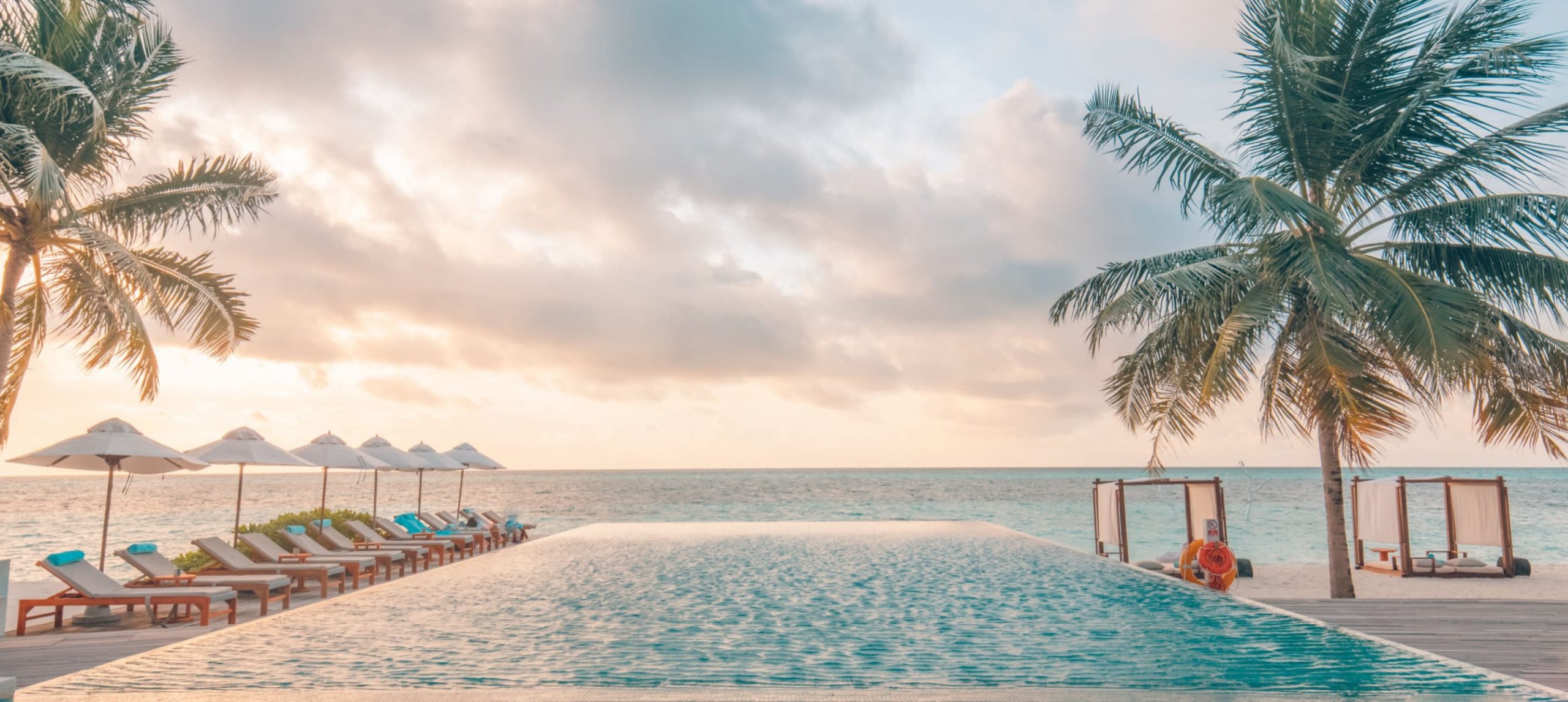 The inifity pool of a luxury beach hotel at sunset.