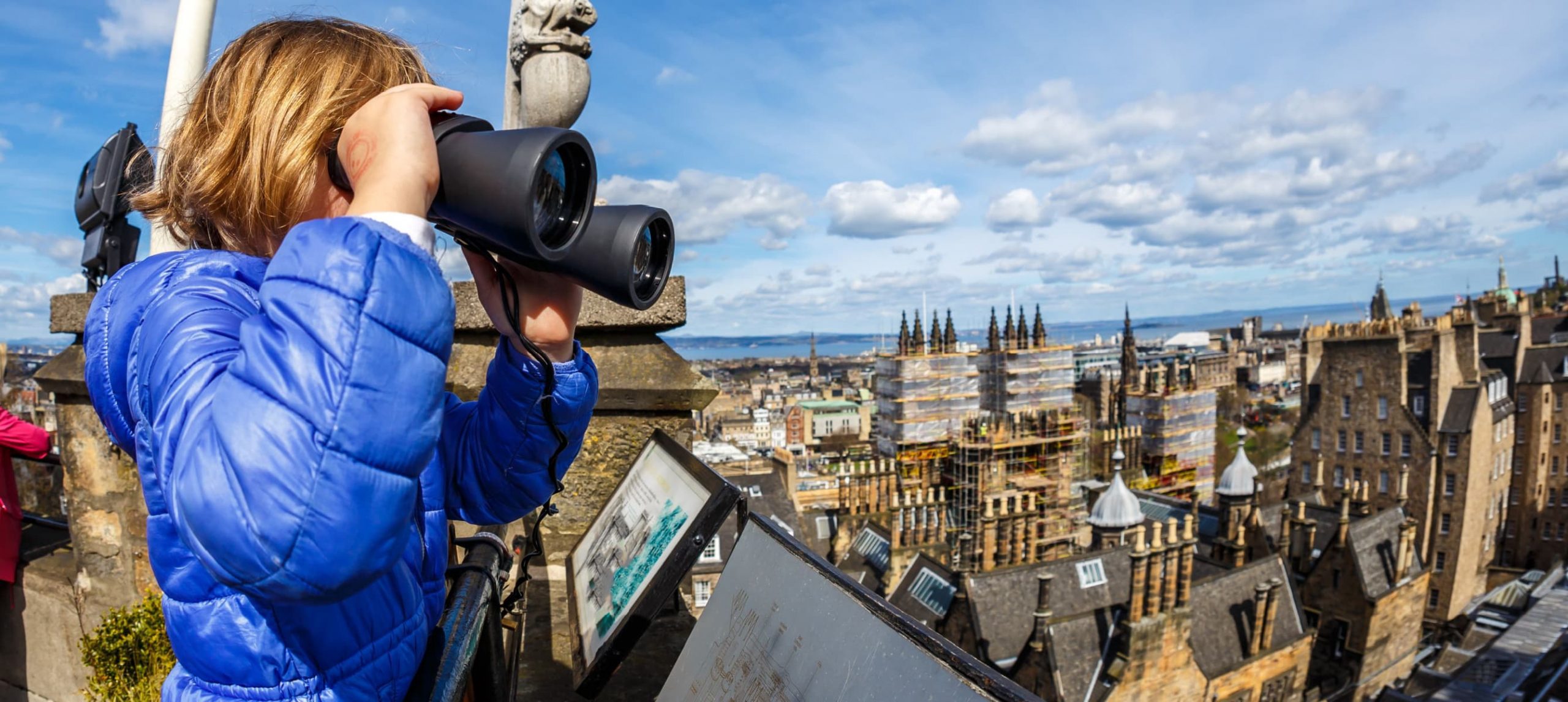 A young girl marveling at Edinburgh's skyline from a rooftop terrace.