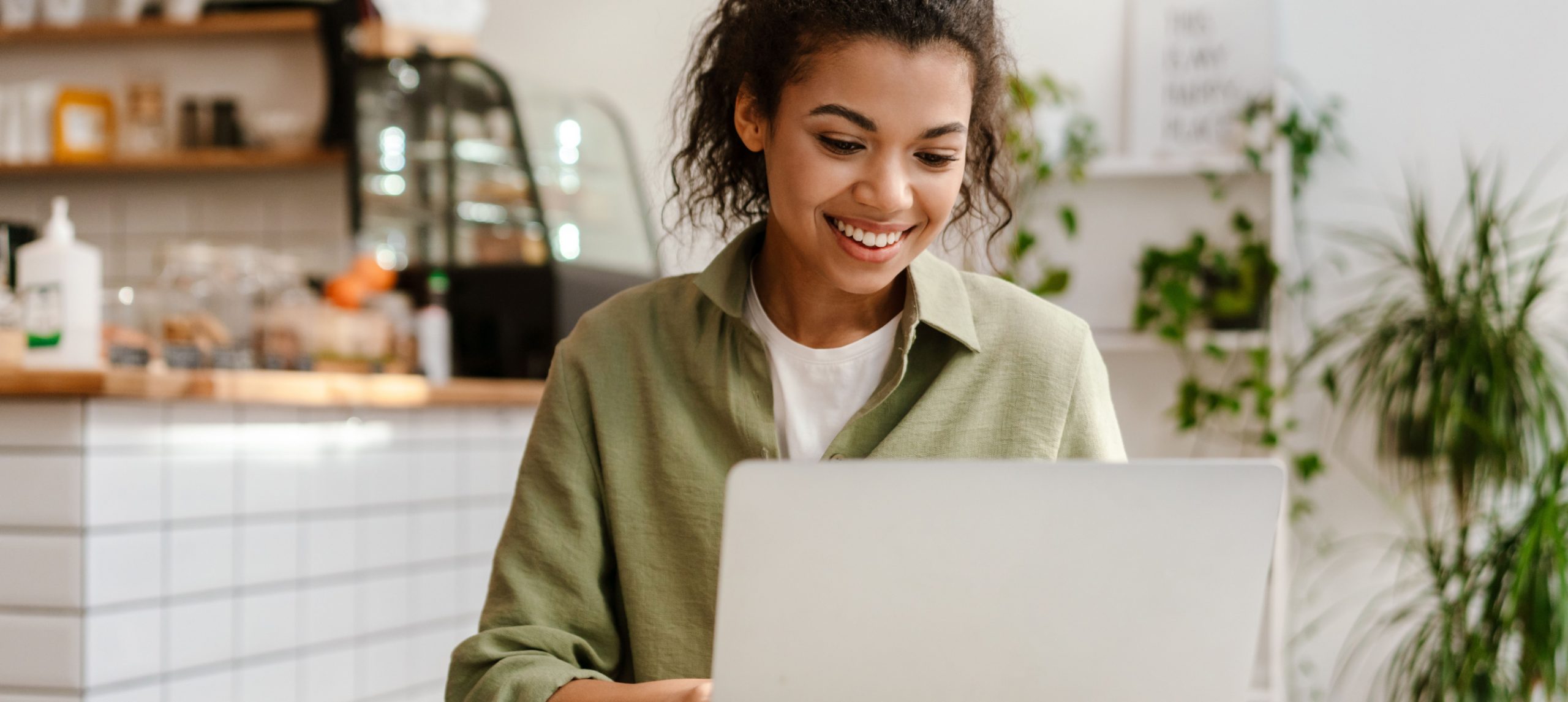 Woman happily working on her laptop at a cafe.