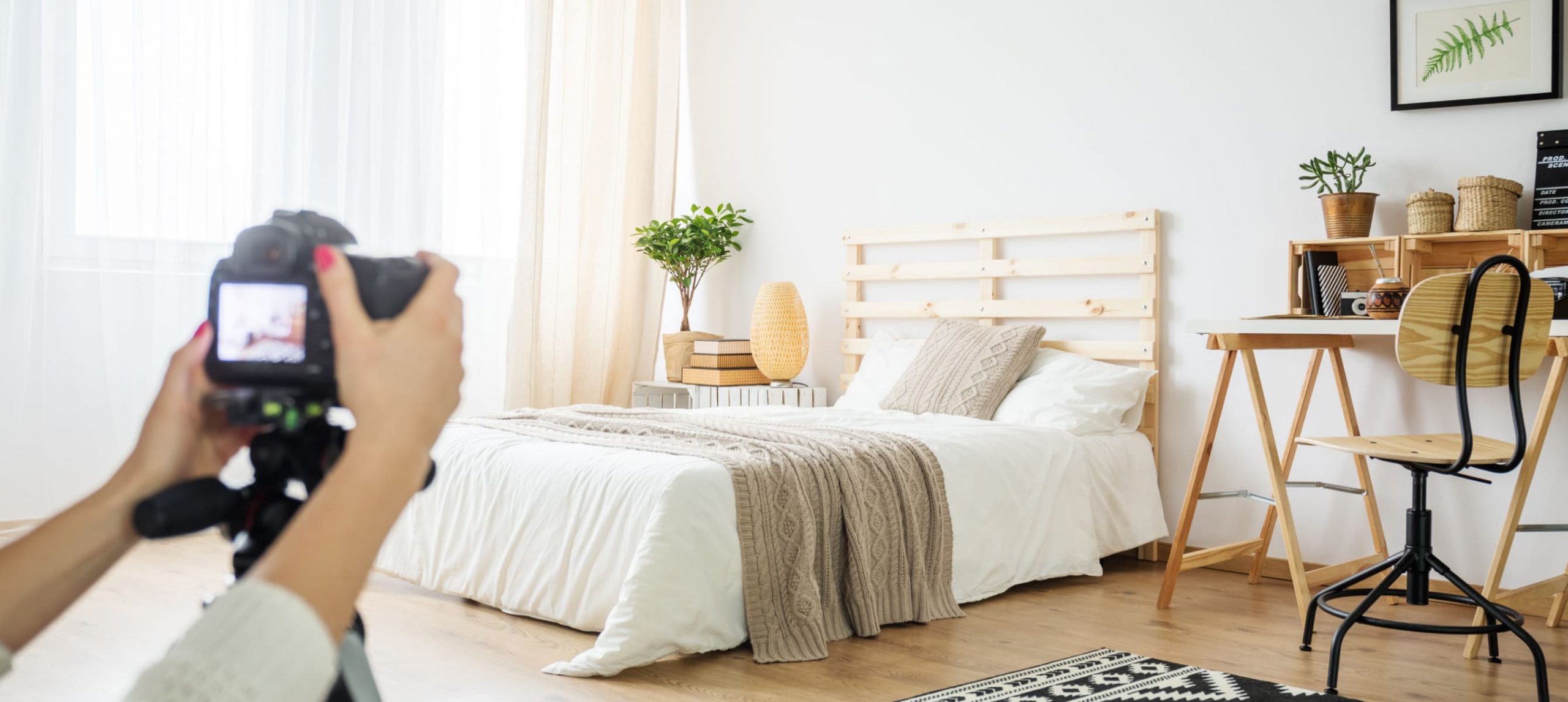 A woman photographing a bedroom with a professional camera.