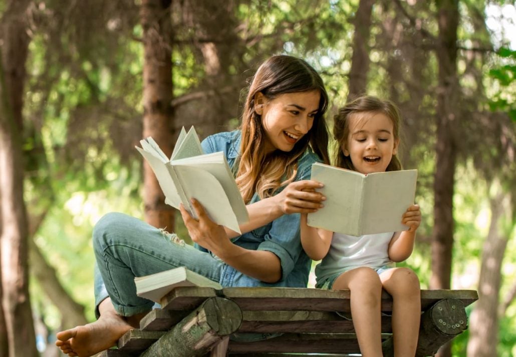 mom and daughter reading books at the park